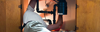 Photo of a plumber working in a cabinet