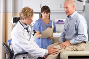 Photo of a doctor examining a male patient with knee pain