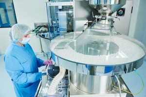 Photo of a pharmaceutical worker operating a packaging machine